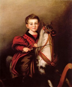 A young boy wearing red shown on a rocking horse. 